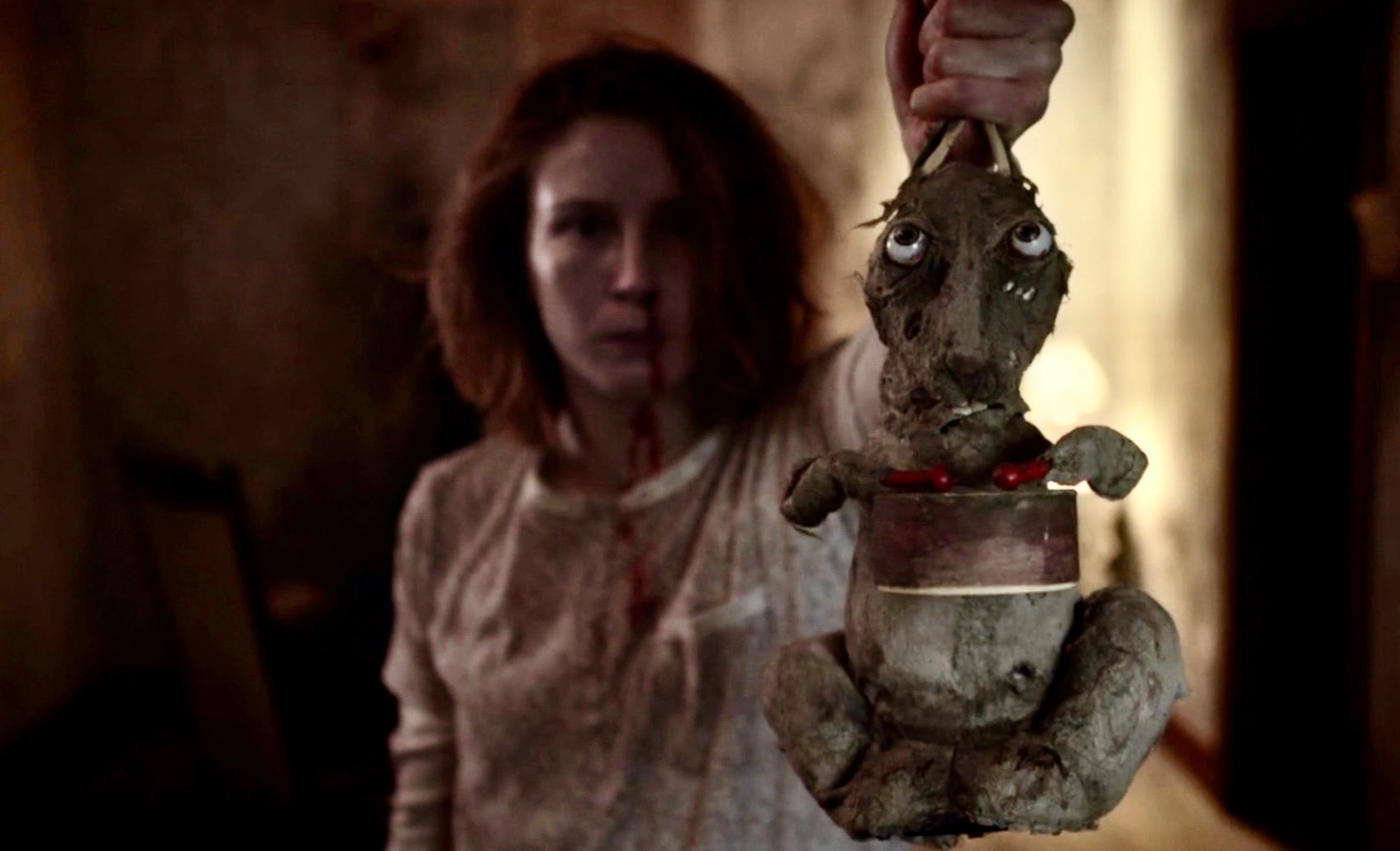 A woman with a bloody nose holds a stuffed bunny in a dark house in Caveat